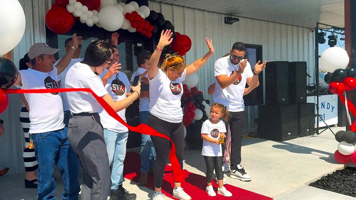 People celebrating the grand opening of the STX Supply & Services shop in Odessa, Texas, cutting the red ribbon.